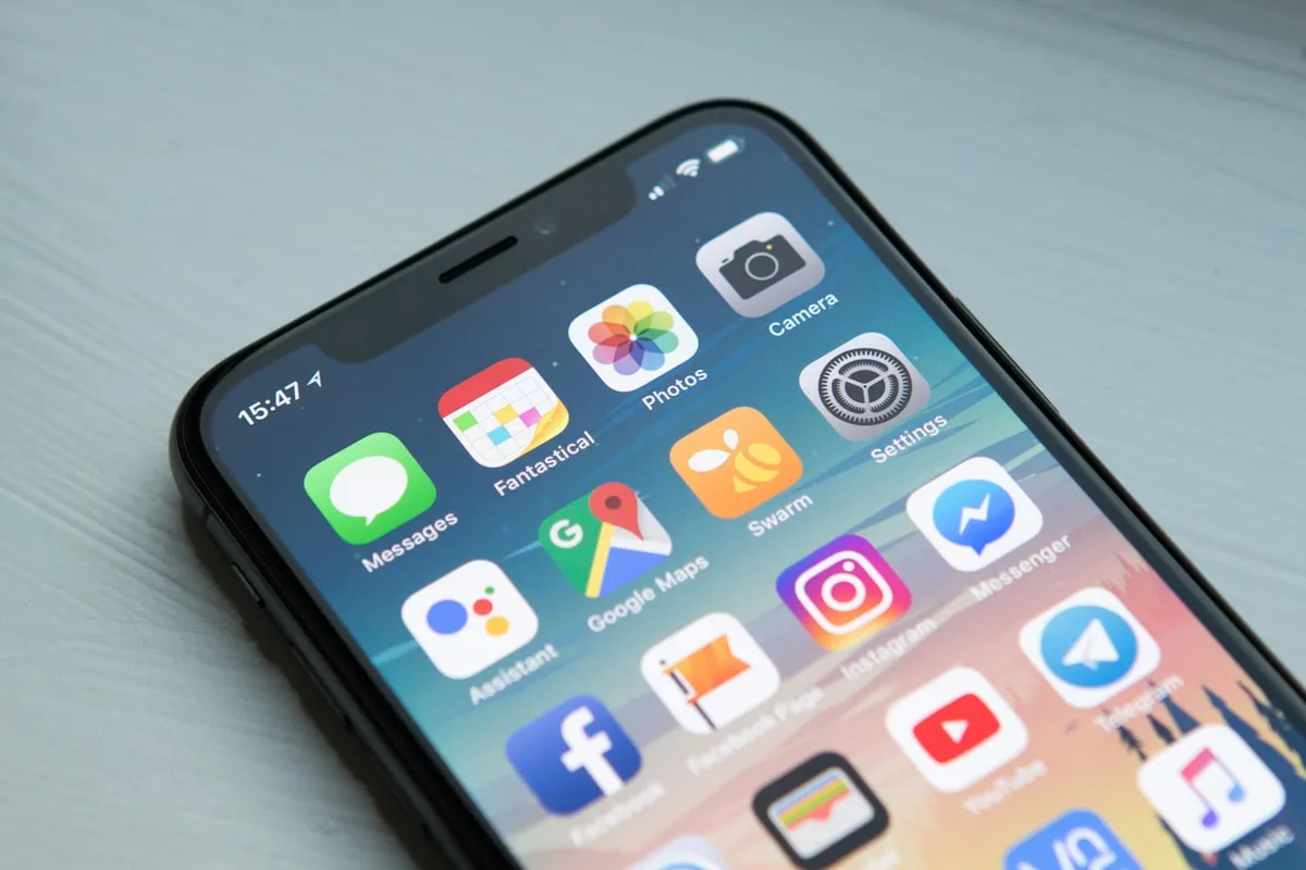Developer reviewing iOS and Android mobile app interfaces on smartphone in London office